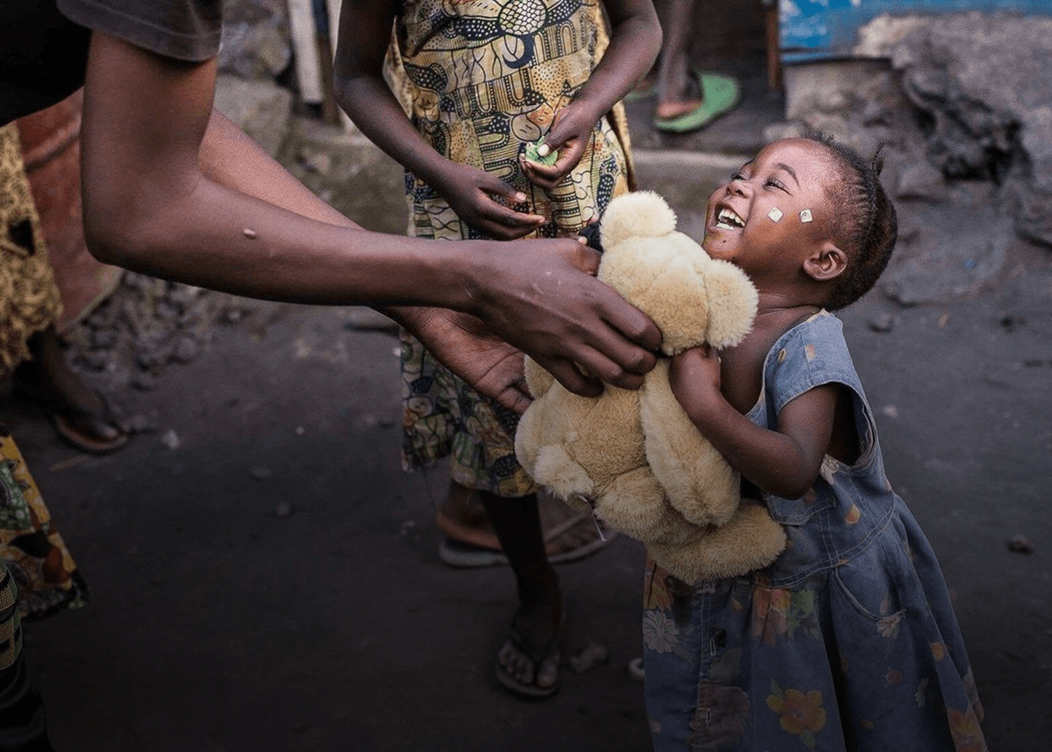 A child laughing while holding a teddy bear
